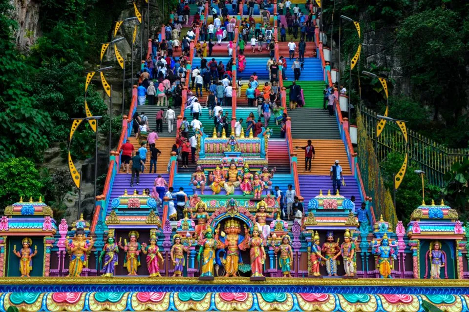 Visitors climbing the rainbow-painted 272 steps at Batu Caves, seen head-on from the base